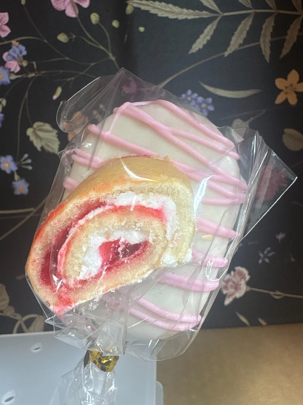 A wrapped swirl treat with white coating and pink drizzle.