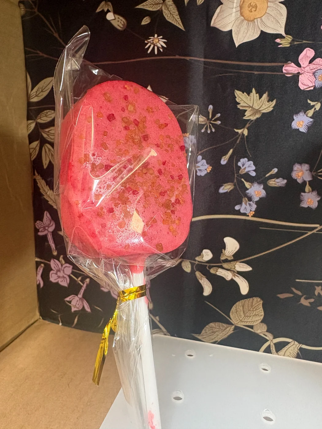 A bright pink wrapped treat topped with colorful sprinkles.